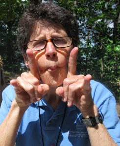 Susan Knight and her legendary impersonation of a carnivorous bladderwort plant. She has her lips puckered out and is holding her two index fingers up her cheeks.